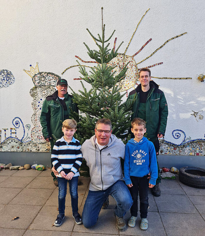 Einrichtungsleiter Michael Vierrath (Mitte) freut sich mit Moritz und Theo sehr über den Christbaum, den Peter Hubeler (hinten links) und sein Sohn Jonas der Kita Am Steinberg gespendet haben. Foto: Kita Am Steinberg